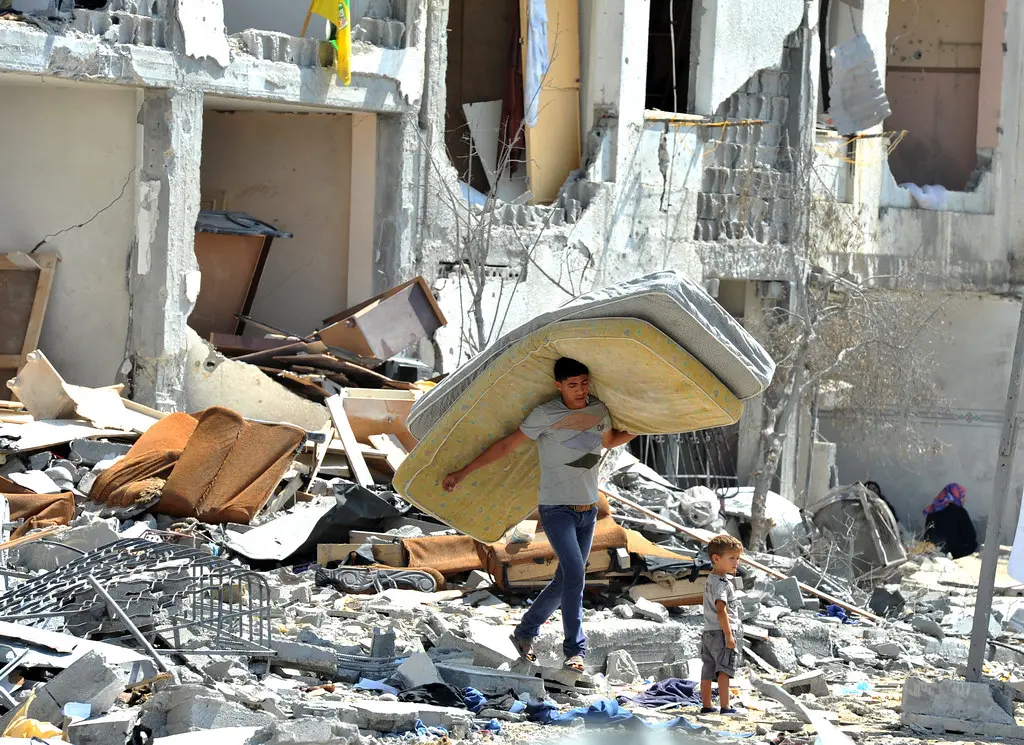 Jovem palestino vasculha os escombros de sua casa destruída por ataques israelenses em Towers Al-andaa, no norte da Faixa de Gaza, em 2014. <br> (Foto: UN Photo/Shareef Sarhan/Flickr)